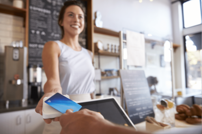 Lachende vrouwen die een Square-betalingstoestel gebruiken om geld af te schrijven van een creditcard