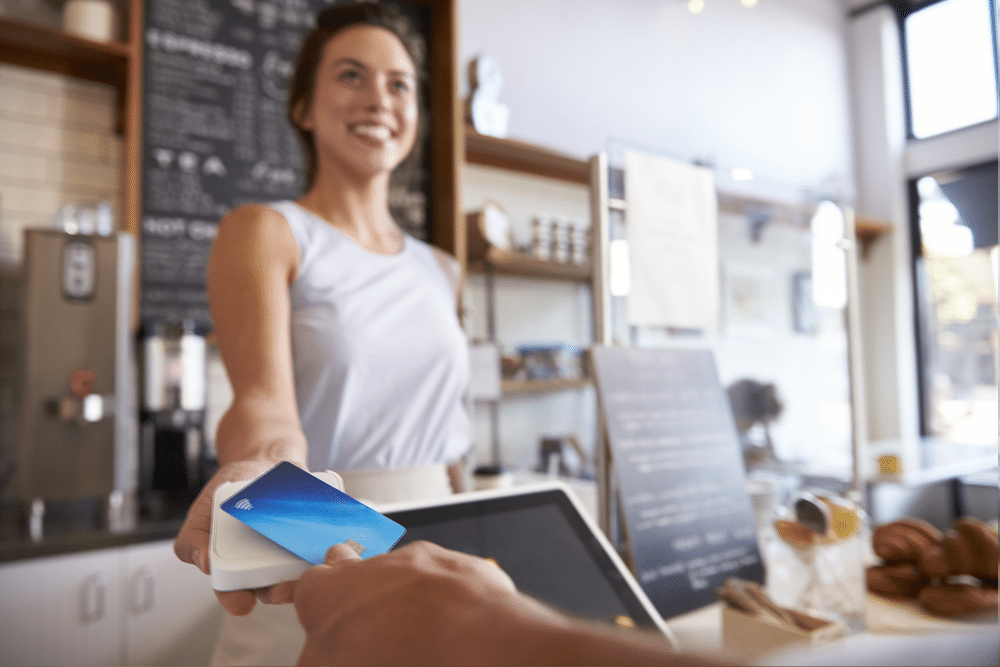 Femmes souriantes utilisant un dispositif de paiement Square pour déduire le paiement d'une carte de crédit