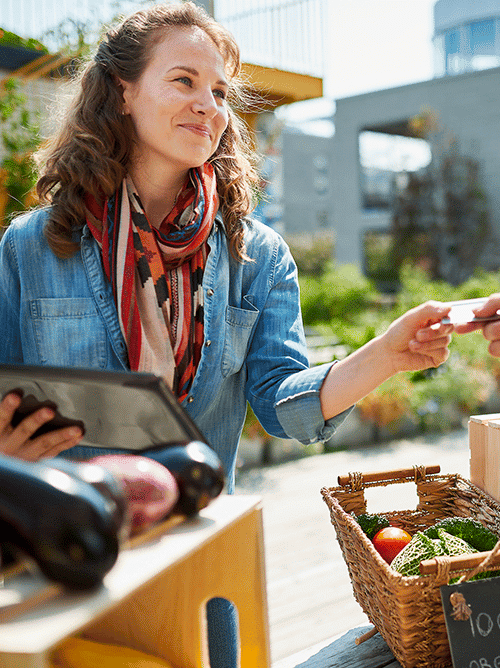 Home 2 Women Handing A Credit Card To A Cashier At A Vegitable Food Market.